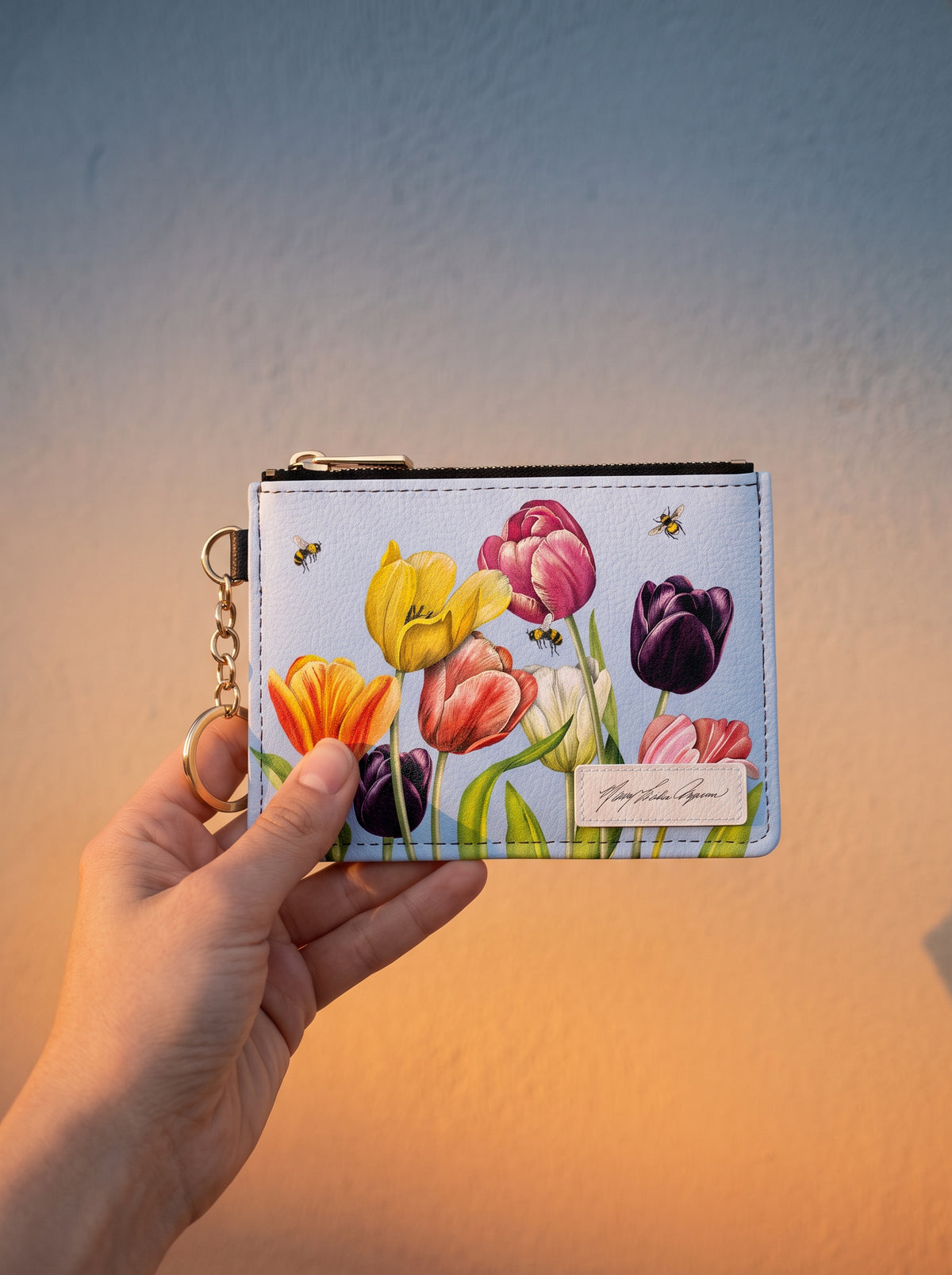 Mary Lake-Thompson Tulips keychain wallet held up against a sunset-lit wall