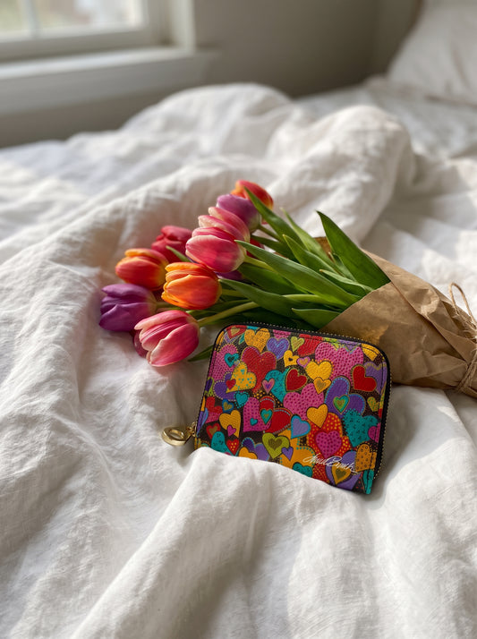 Monarque Laurel Burch Dancing Hearts zipper wallet on white bedding with tulips
